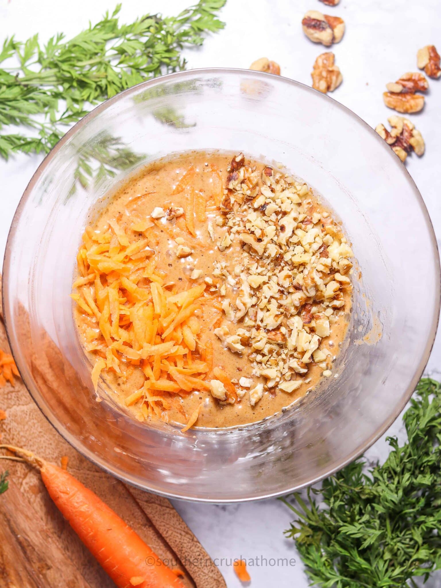 carrots and walnuts in mixing bowl with carrot cake batter
