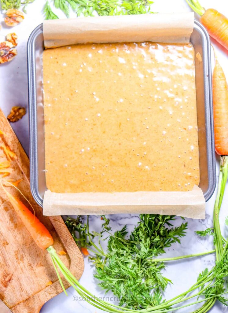carrot cake batter in baking pan with parchment paper