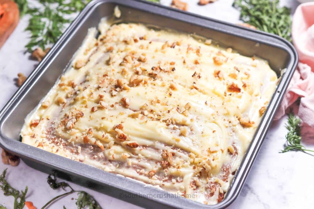 walnuts sprinkled on top of frosted carrot cake