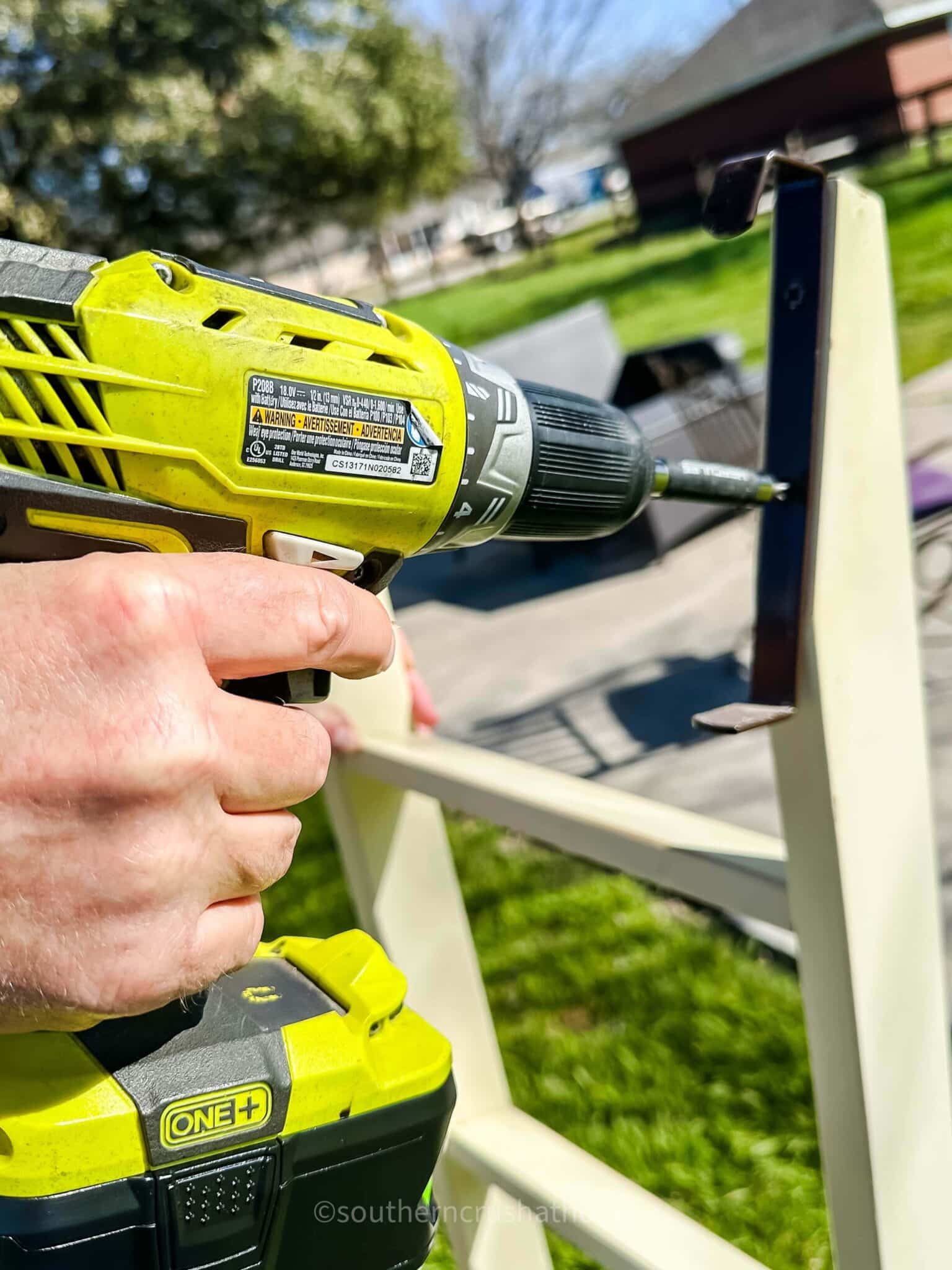 using a drill to remove a metal bracket