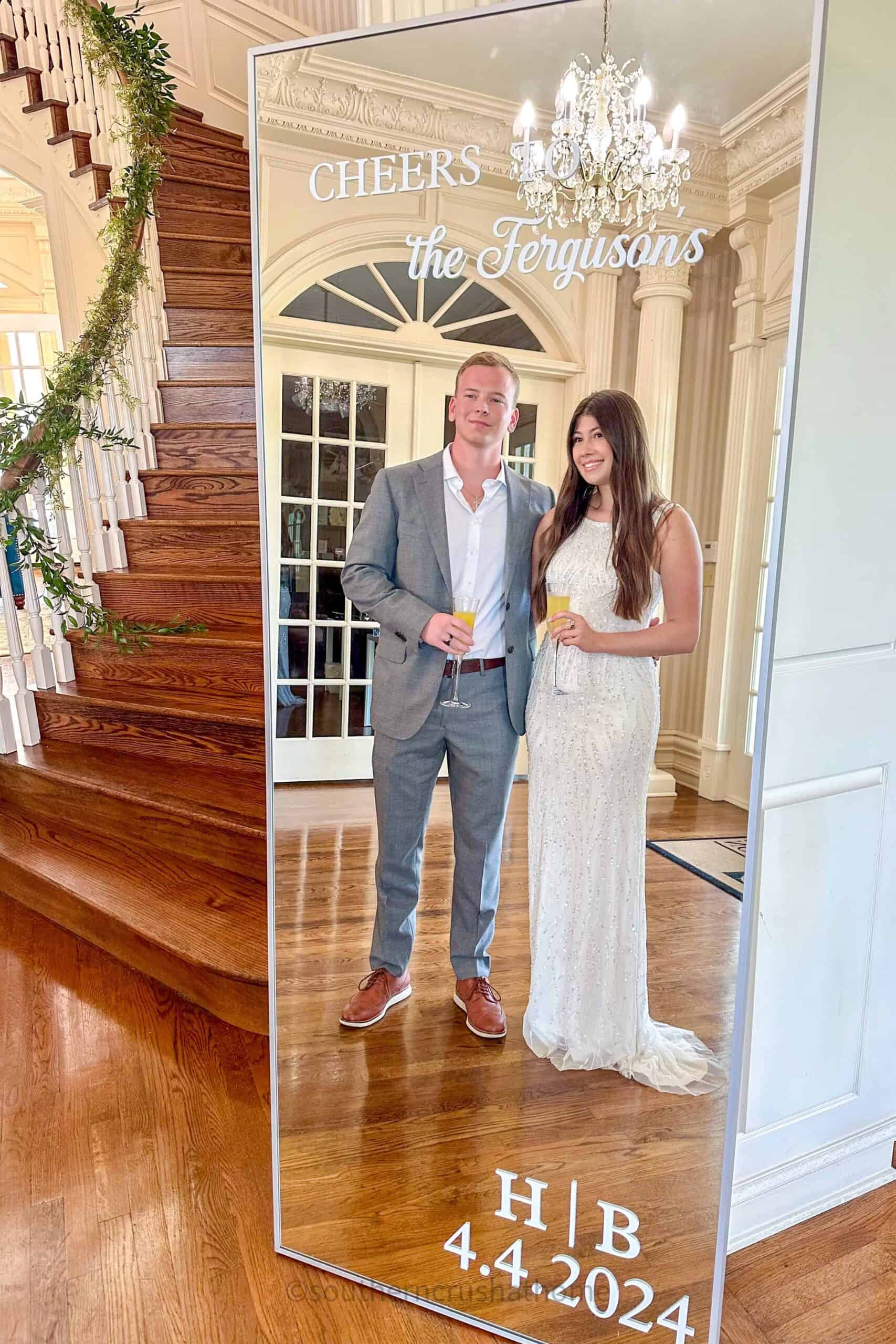 Brady and Hadley Ferguson in front of wedding welcome sign mirror