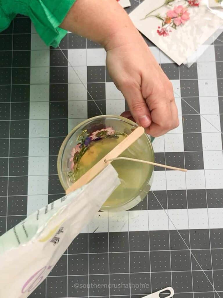 pouring the candle wax into the tea cup with dried flowers