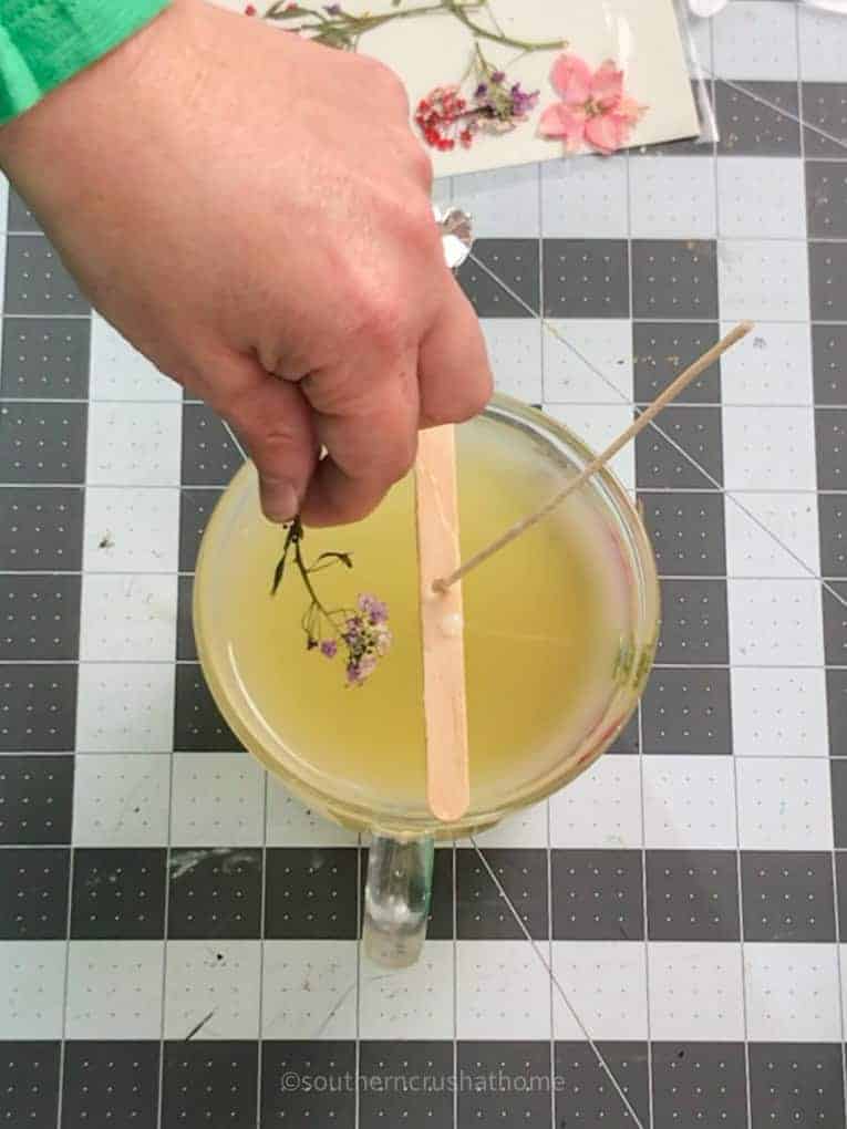 placing dried flowers into candle wax