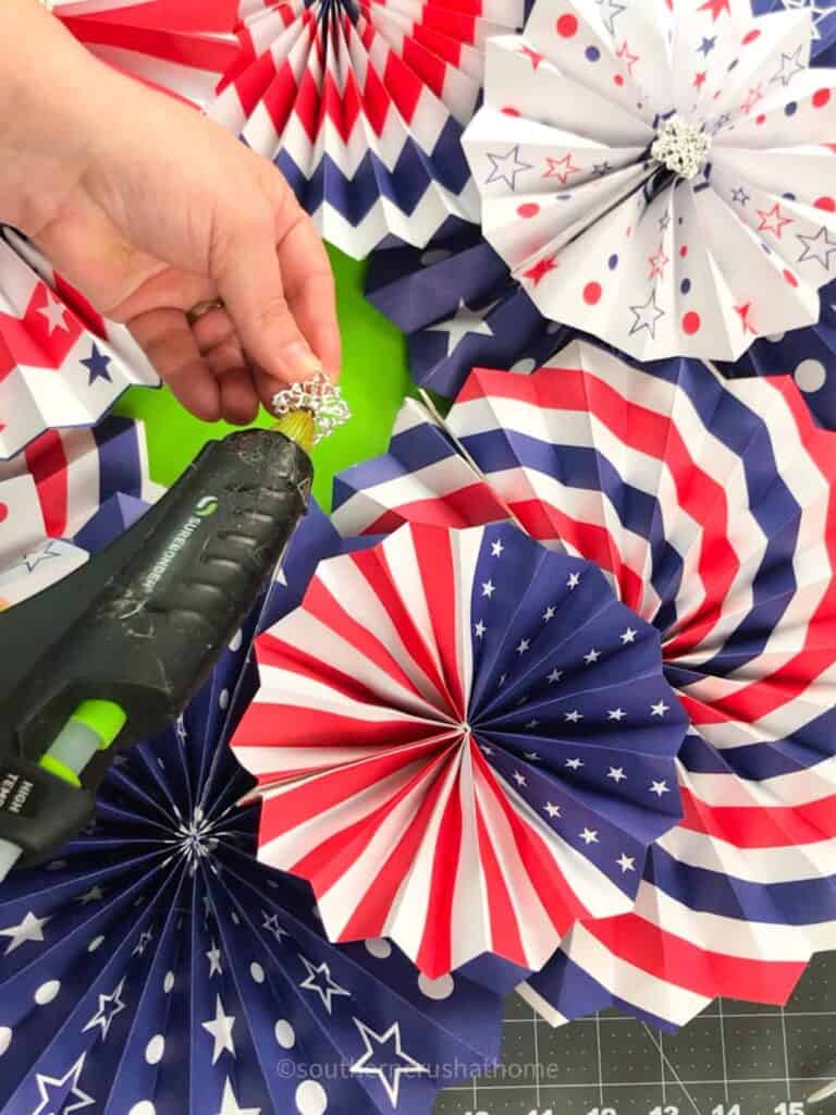 adding bling embellishments to center of paper fan using hot glue