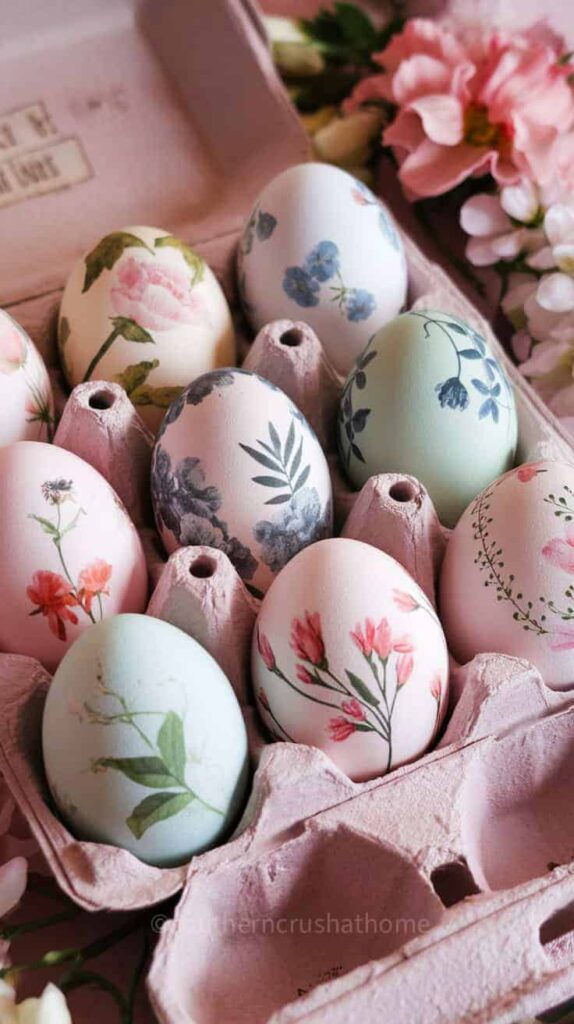 A variety of Easter eggs with botanical prints and floral patterns arranged in a pink carton.
