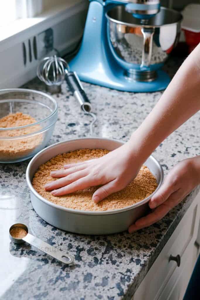 pressing graham cracker crust in a springform pan